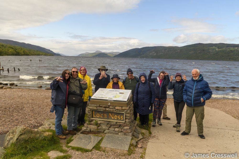 Group of people standing by a sign on a lake shore